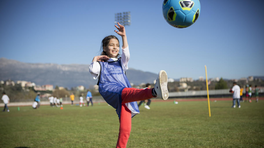 Young girl kicks ball during a refugee solidarity event. National football associations across Europe are stepping up to help welcome refugees into their new communities.