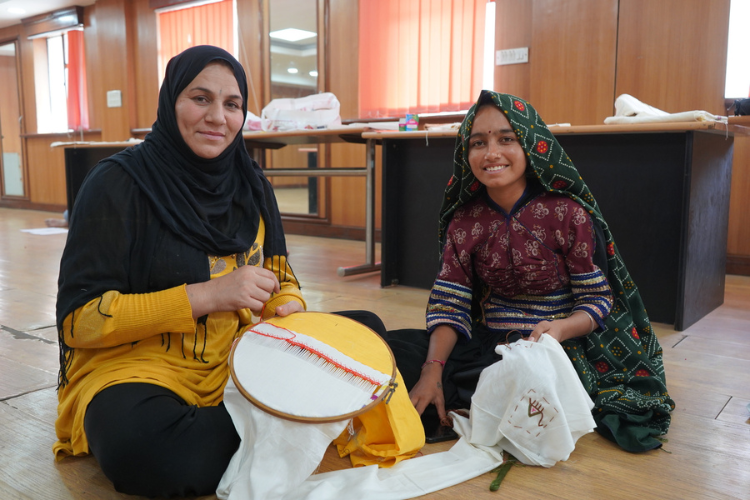 Artists Farida and Rasilaben weave together during the Embroidery without borders workshop, exchanging stitches shaped by generations. 