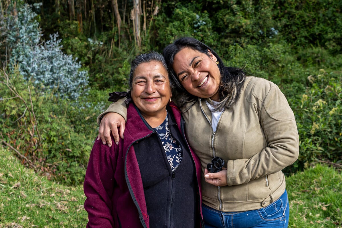An Ecuadorian woman, 67, and a Venezuelan woman, 39 embrace and celebrate their friendship on the banks of a river.