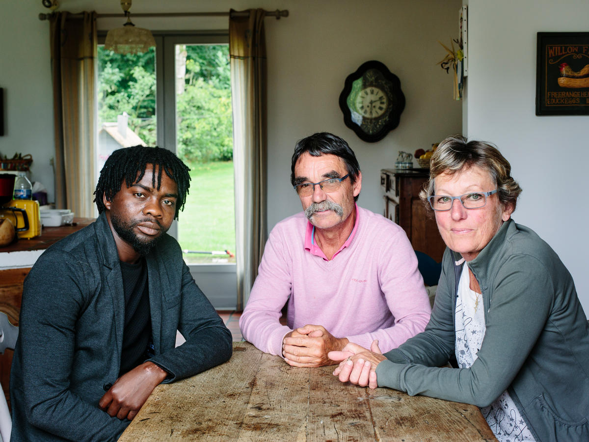 France. Catherine and Jean-Pierre host Assadik, a refugee from Sudan, in Saint-Josse. This portrait is part of the No Stranger Place series, which portrays locals and refugees living together
