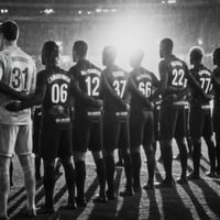 AI-assisted rearview image of a football team lined up on the pitch inside a brightly lit stadium 