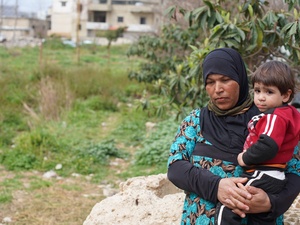 A Syrian woman holds her young nephew in a field near their home