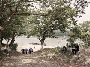 A group of people walk away from a river bank.