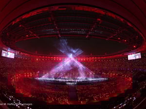 Beams of white light form a giant cone in the centre of a darkened stadium as part of a light-show.