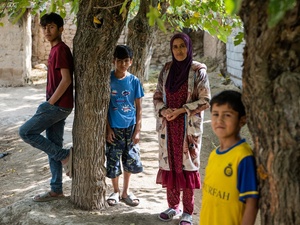 A woman stands amongst some trees with three boys of different ages.