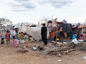 Children walk along a dirt road in a transit centre