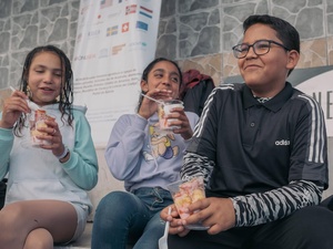 Three children laughing while eating dessert outside