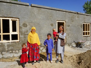 A man holding his child stands with his wife and two children in front of a newly built apartment.