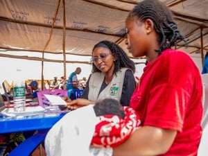 A woman siting in a UNHCR registration centre while holding her baby