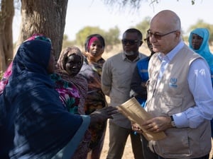 Barham Salih speaks to refugees and community members outside beside a large tree