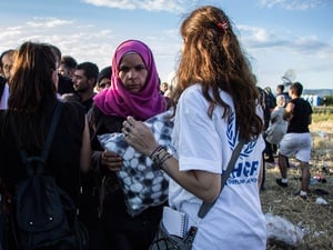 A UNHCR staff member distributes blankets to people waiting to cross the Greek-FYR Macedonian border.