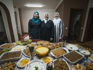 Family of chefs. Syrian refugees Fatima and her daughters Rana and Reem in front of their home cooked dishes.