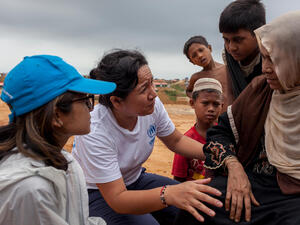 Outside. A women and three children talk with two UNHCR staff.
