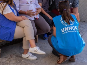 Two UNHCR staff members speak with asylum-seekers in a border town in northern Mexico.