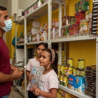 A man and his two daughters browse food items in a small grocery store.