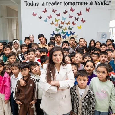 A woman stands in the middle of a classroom full of young students