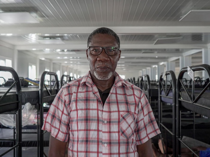Buduka, an asylum-seeker from Nigeria, is pictured inside a bunk-bed-lined dormitory.