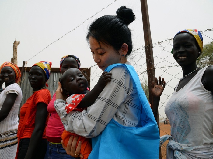 UNHCR's Eujin Byun holds a refugee baby in her arms at a refugee camp in South Sudan. 