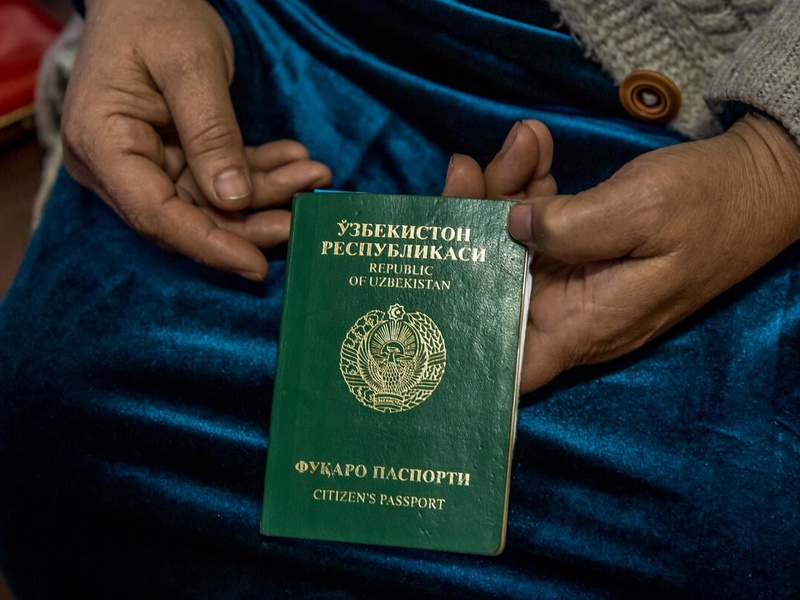 Close up of a woman's hands holding her invalid Uzbeck passport. 