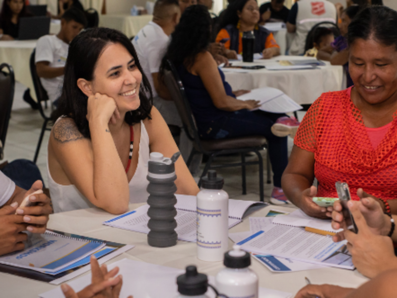 A group of women sit together at a table and consult documents.