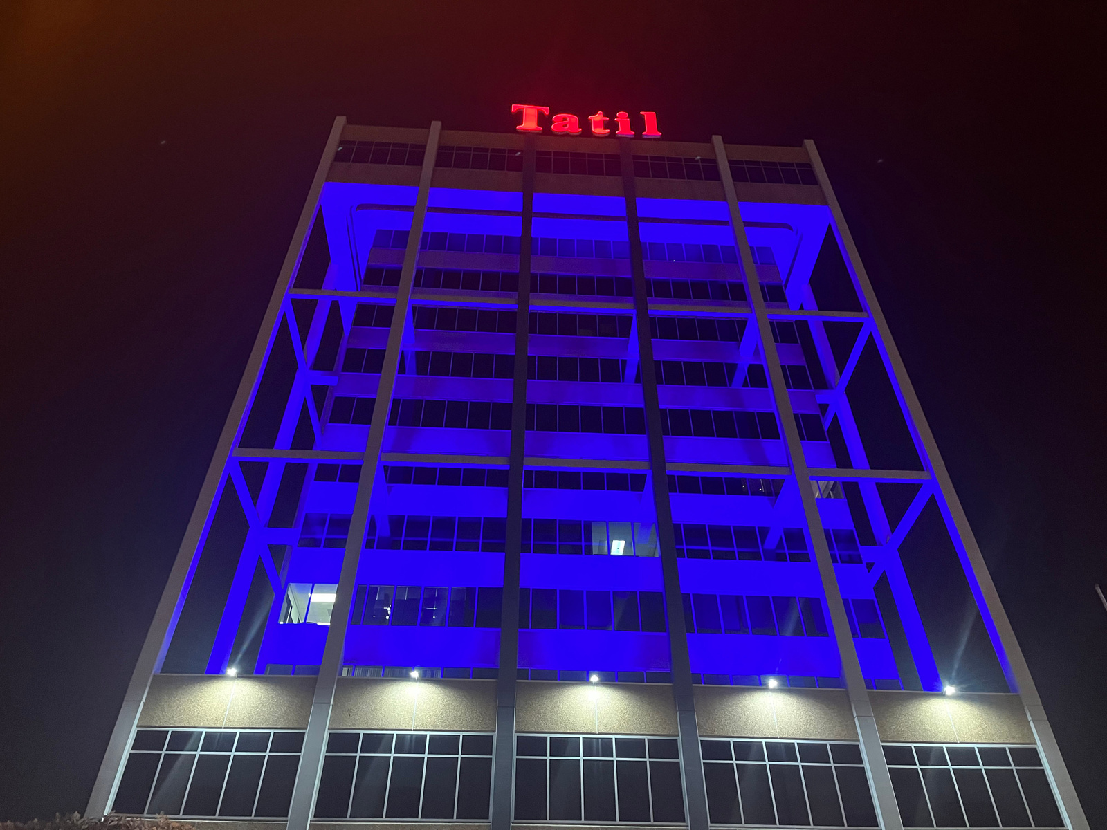 The exterior of a building lit in blue tooped with a red neon sign reading "Tatil"