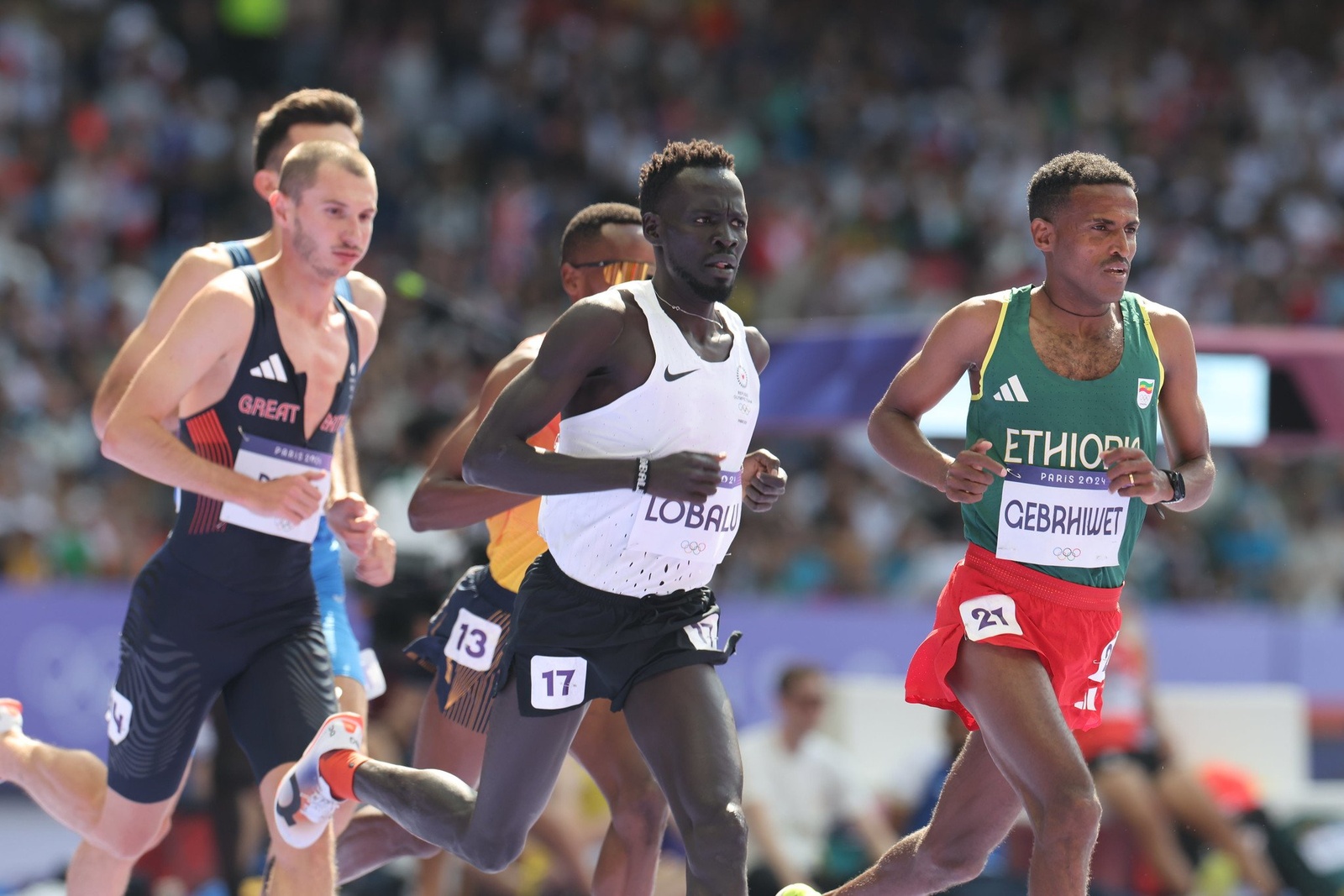 Male athletes run inside a packed stadium