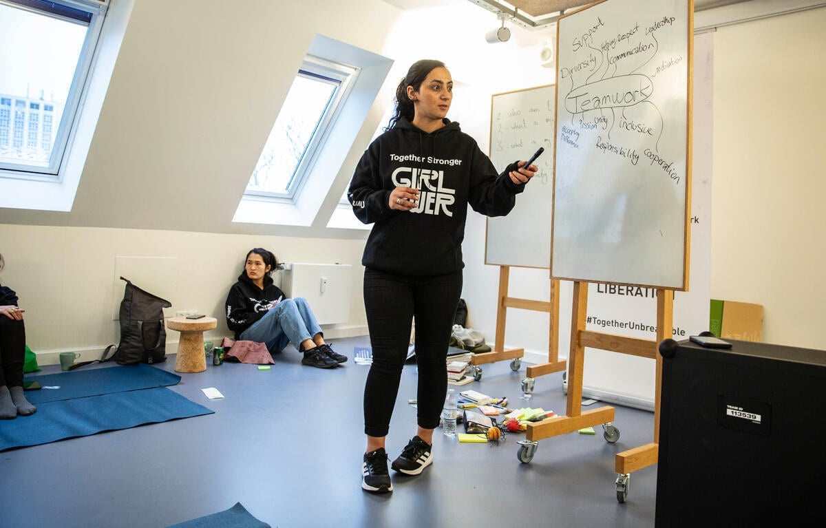 A woman points at a whiteboard while leading a workshop