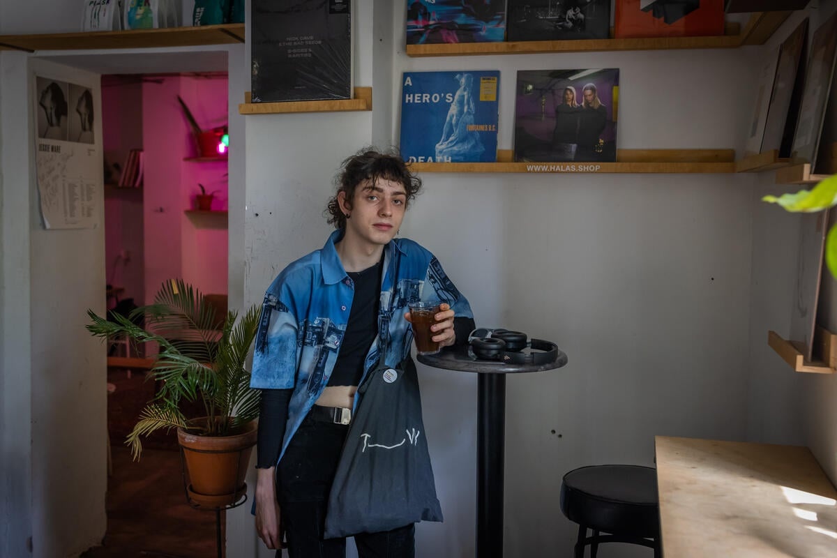 A woman pictured standing and leaning against a table in a café