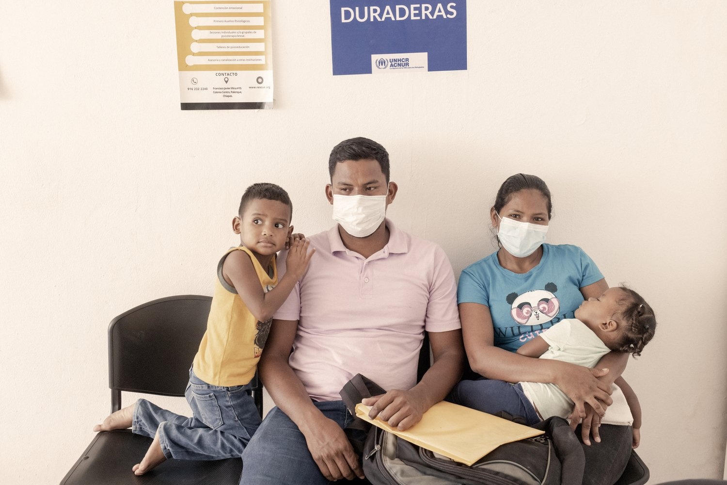A couple wearing face masks with their two young children.