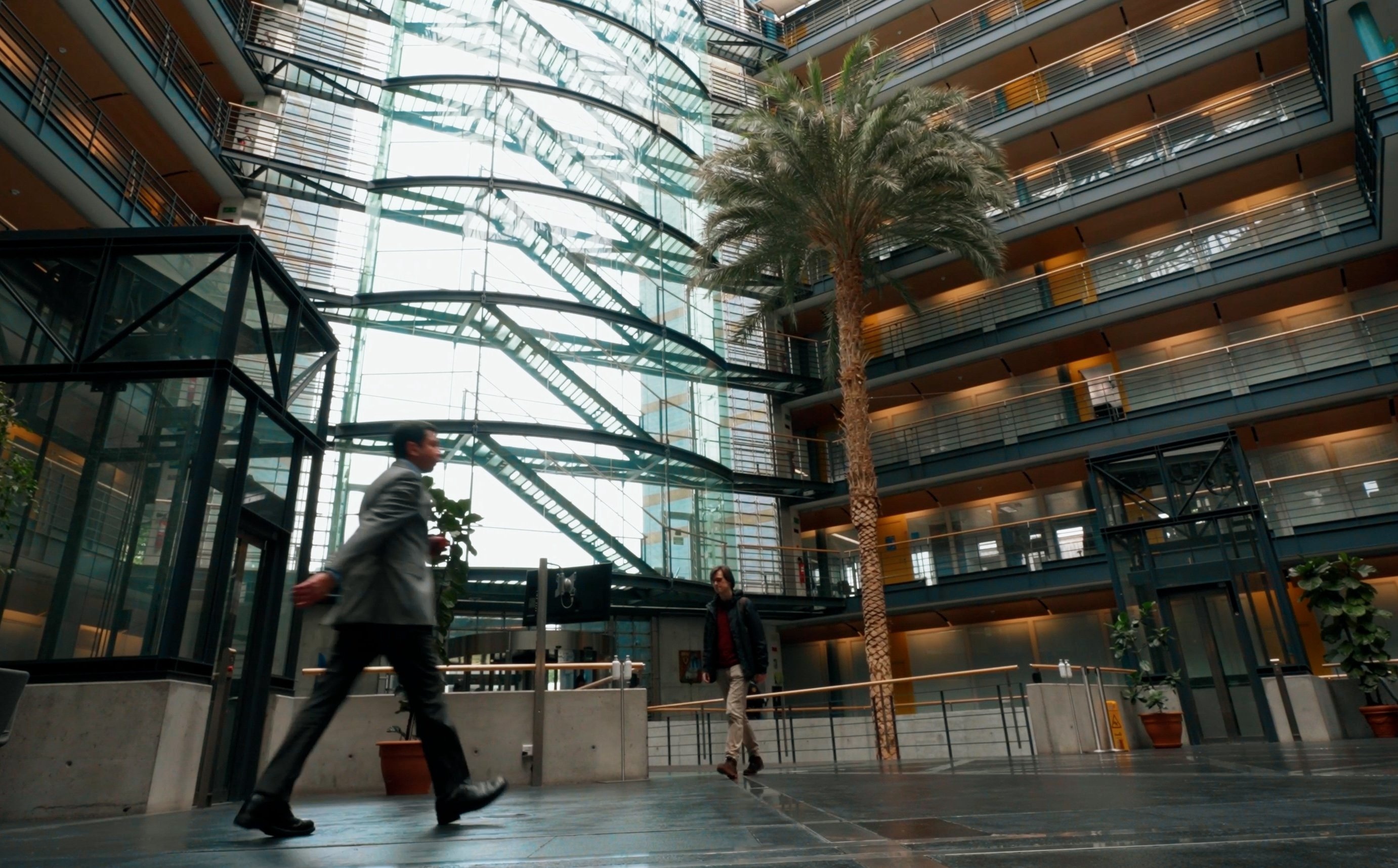 Two men walk through the lobby of an office building