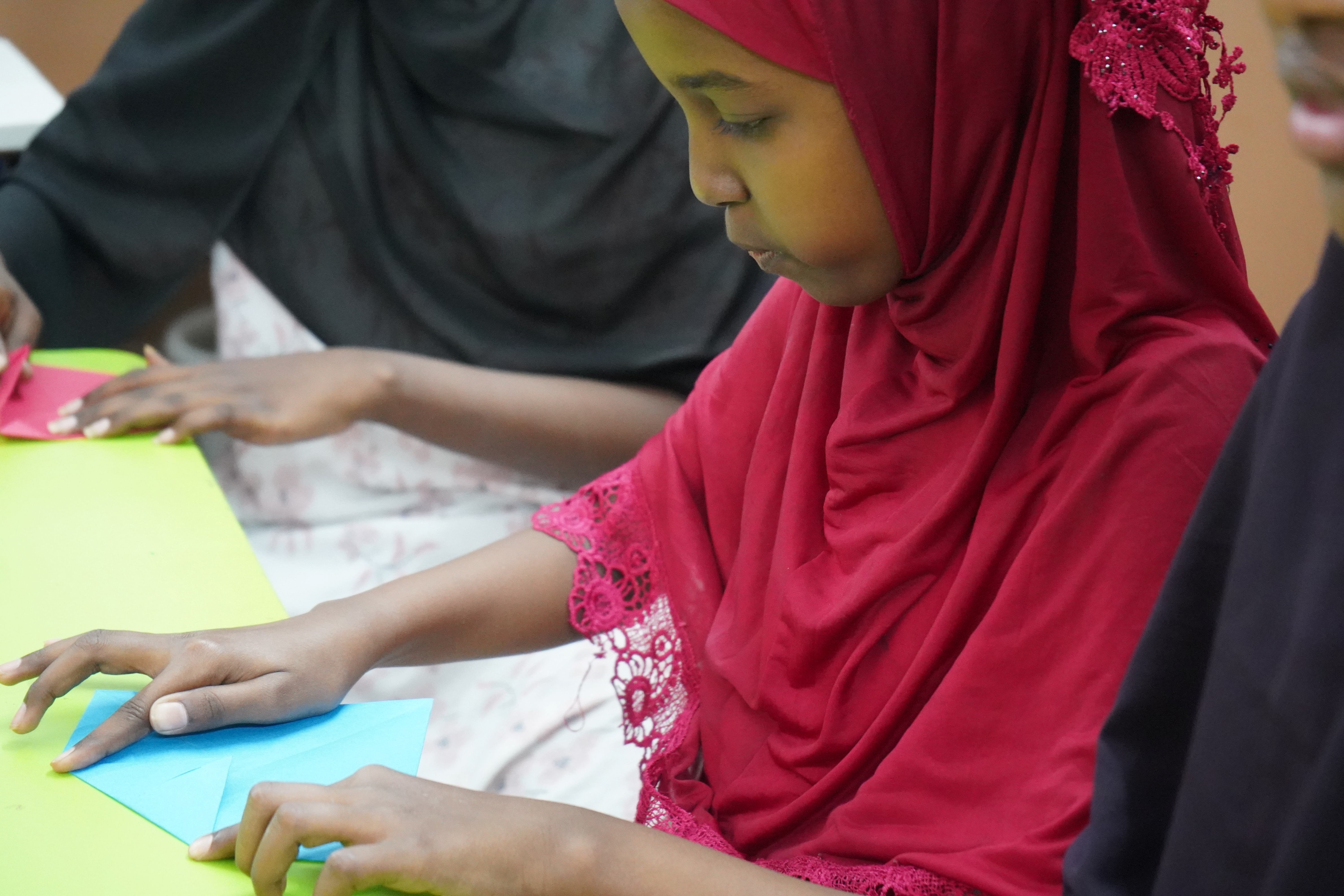 A young girl creates colorful paper lotus flowers during an art session, exploring creativity in a supportive learning environment.