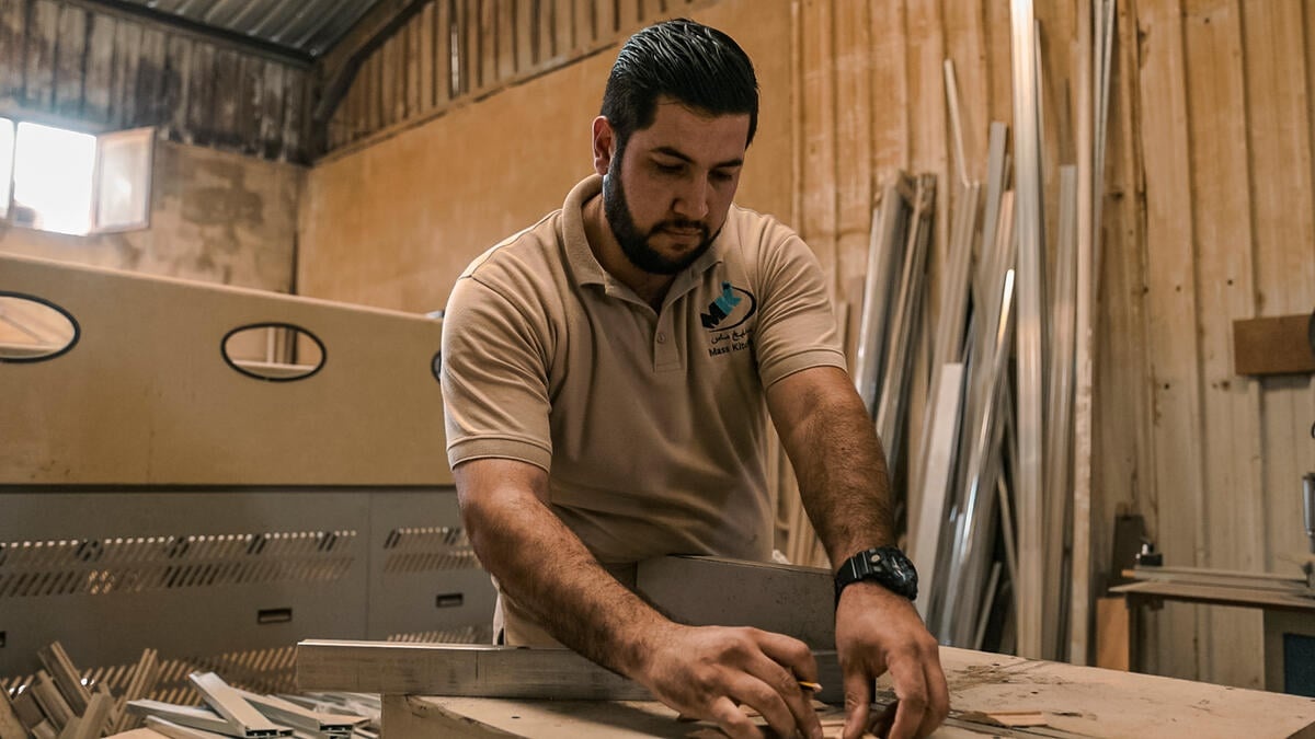 A carpenter measures wood in a workshop.
