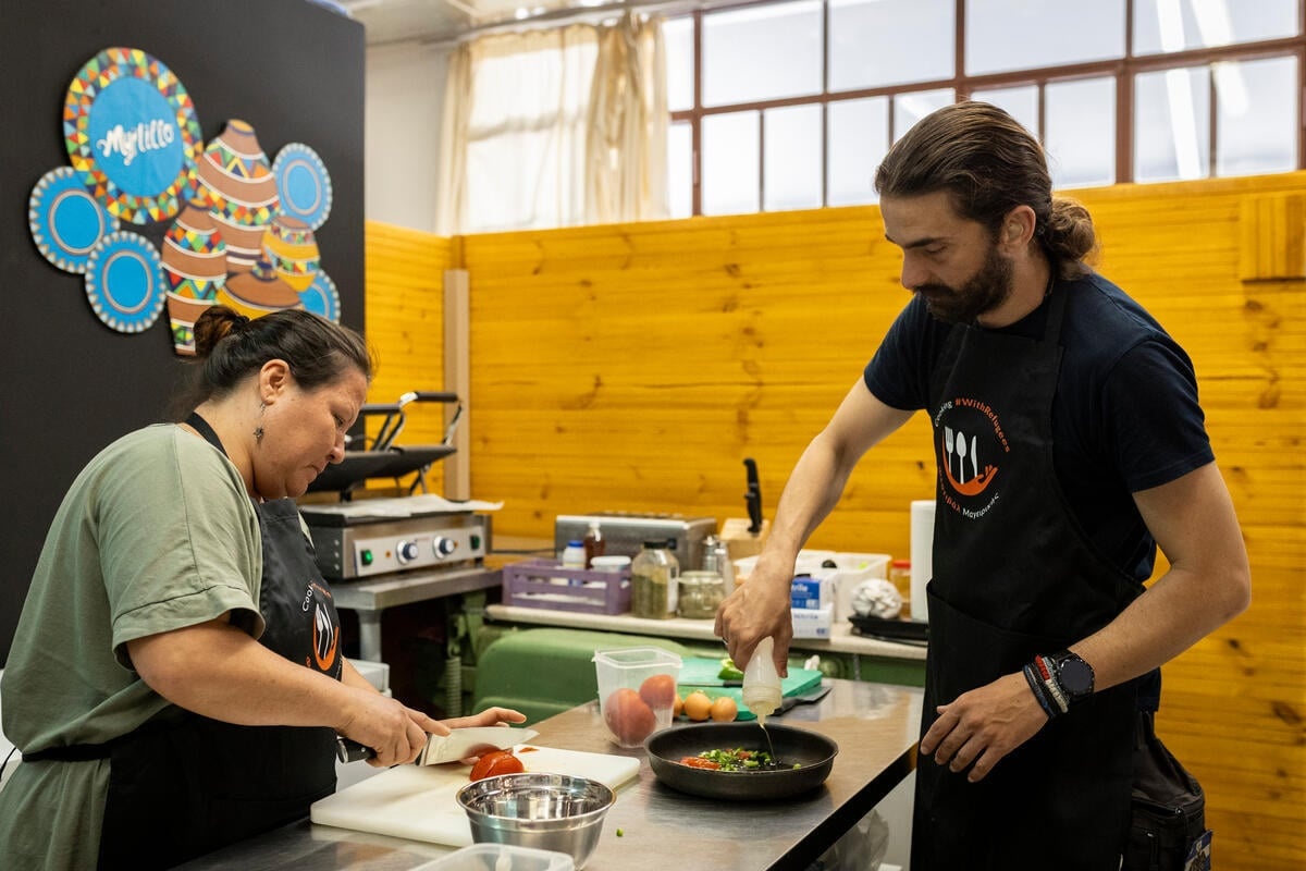 Sardar Hasemi prepares food with Thomas Avlakiotis in a kitchen.