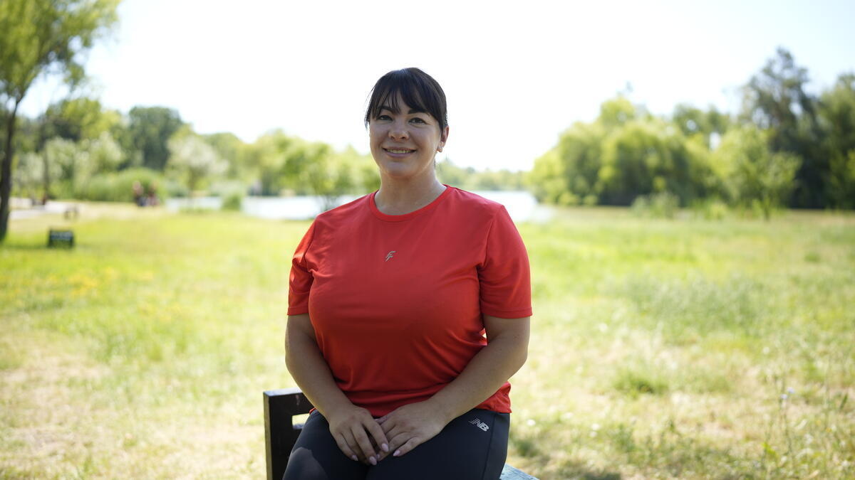 A woman sits on a park bench in front of a lake
