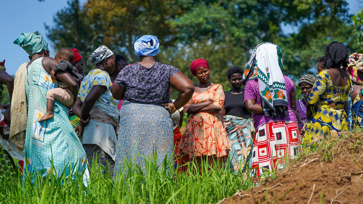 A group of women stand together in a rice field.