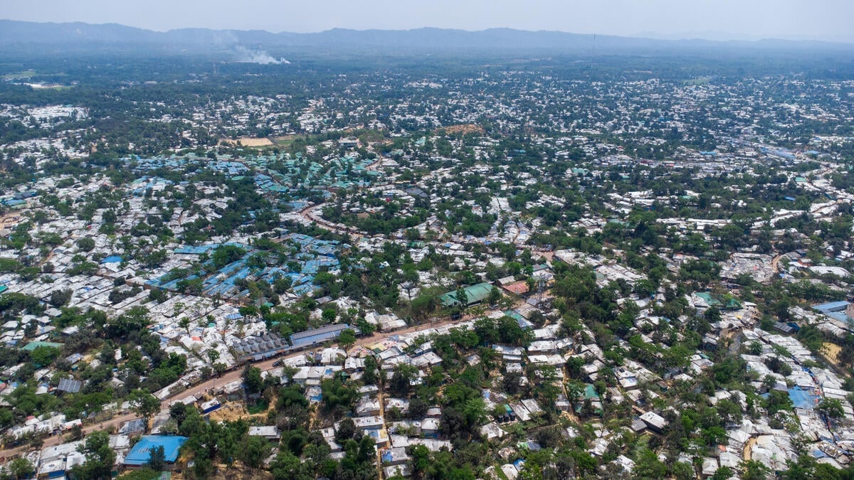 An aerial view of a vast refugee settlement with shelters extending to a mountainous horizon