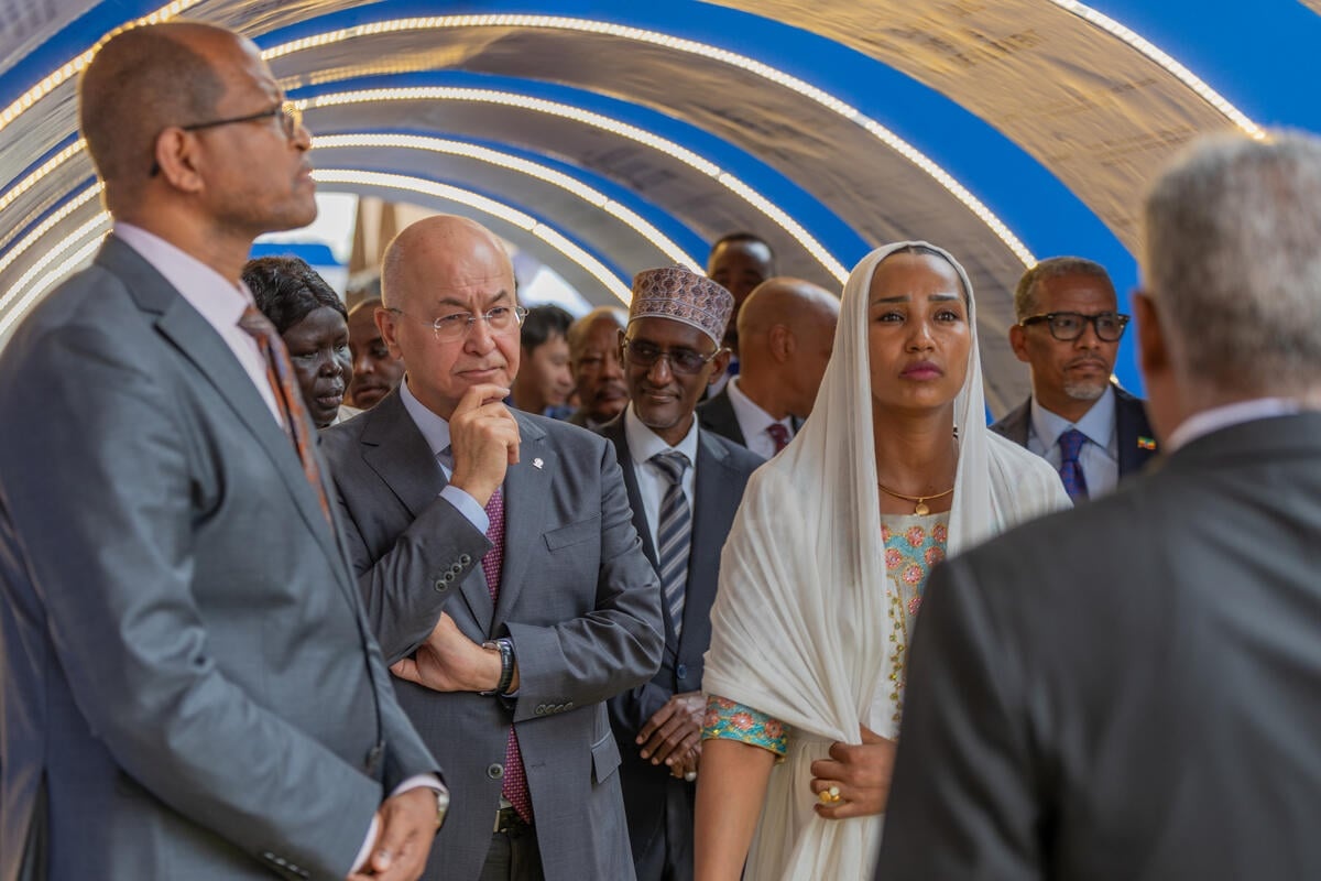 A woman wearing a headscarf stands alongside men wearing suits at a formal event