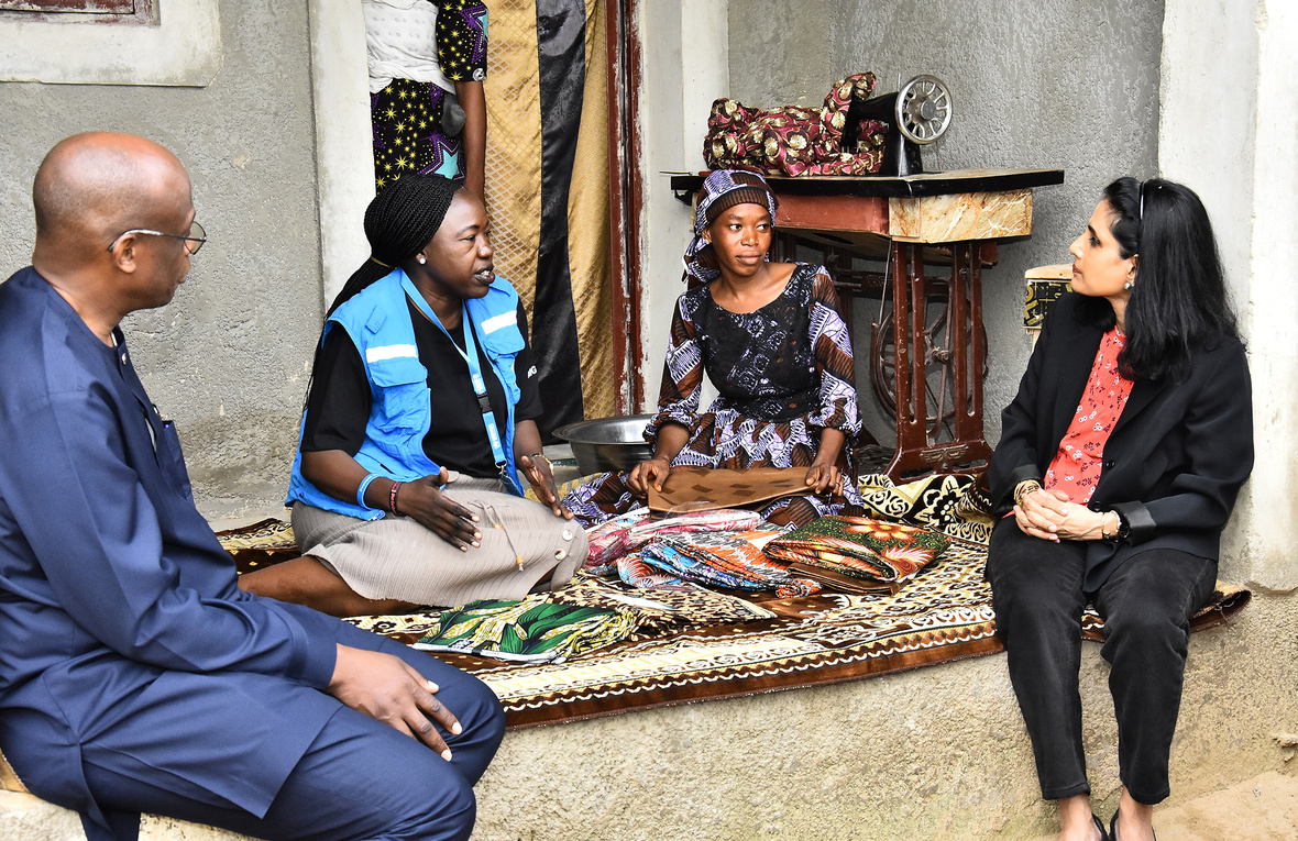 Four people sit together talking on a colourful rug