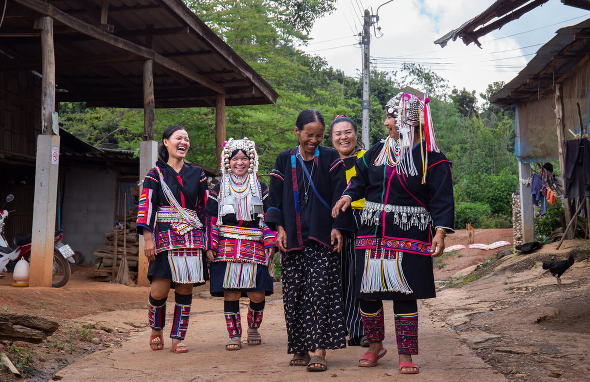 A group of women walk, laughing, through a village in Chiang Mai, Thailand.