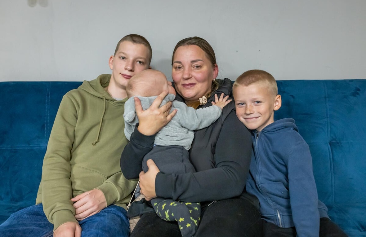 A mother and her three children sit on a couch