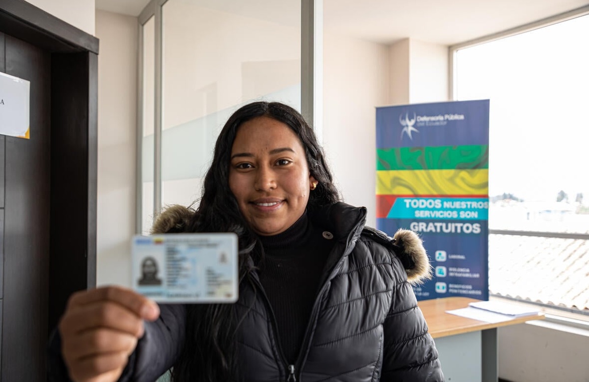 A woman holds up an ID card.