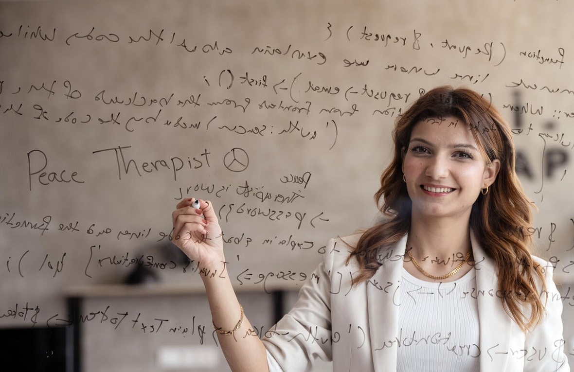 A young woman seen through transparent glass which is writing code on.