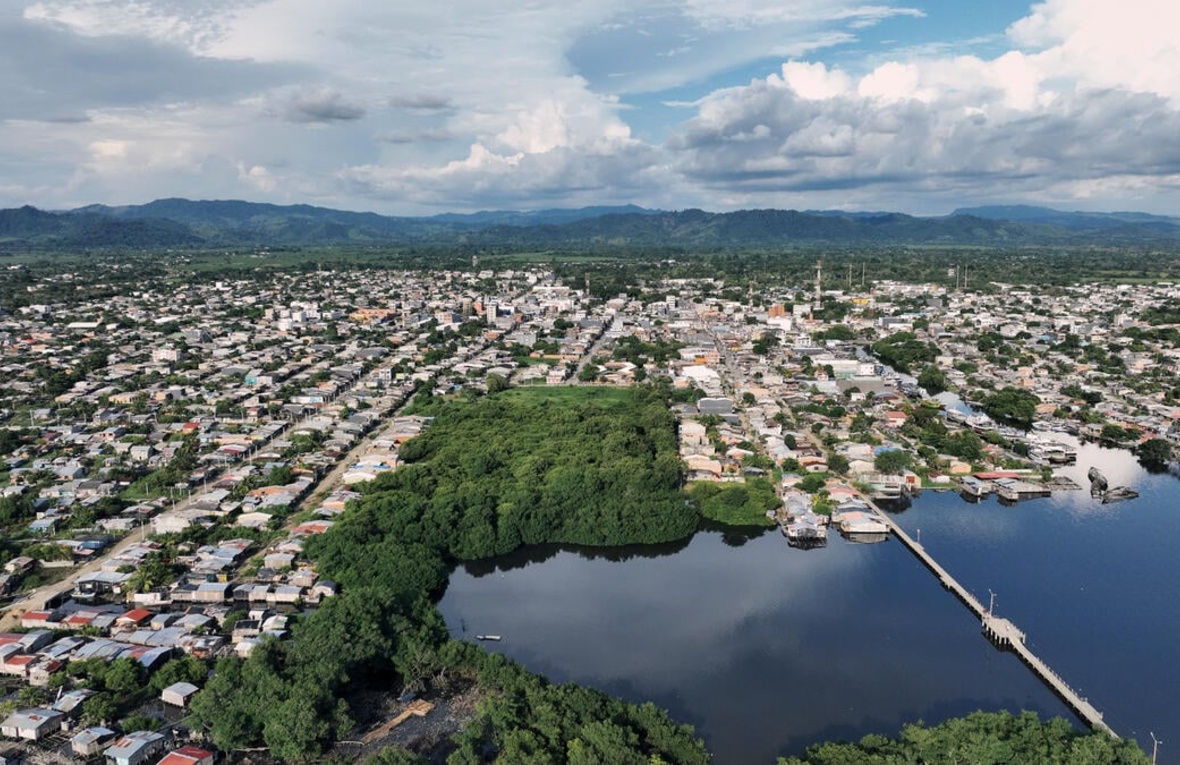 An aerial view of a town and mangroves clustered around an inlet.