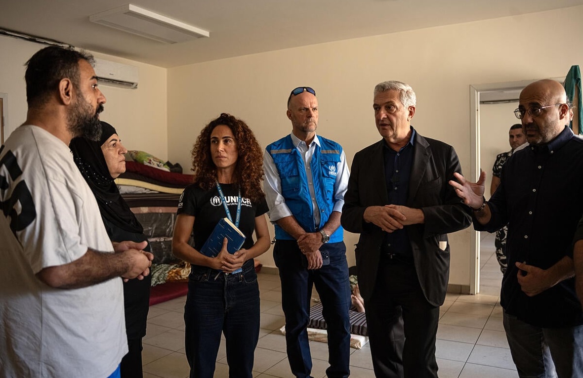 A group of people talk in a classroom that is being used as a temporary dipalcement shelter