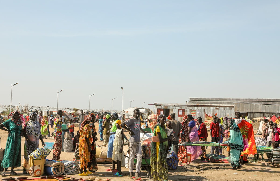 A group of people in colorful clothing gather with their belongings.
