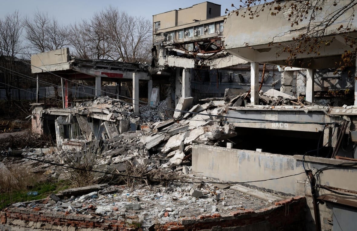 An exterior view of war-damaged buildings with collapsed roofs and walls.