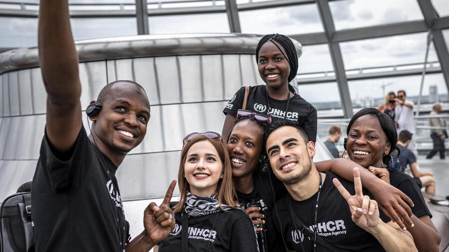 A group of young people in UNHCR t-shirts take a selfie. 