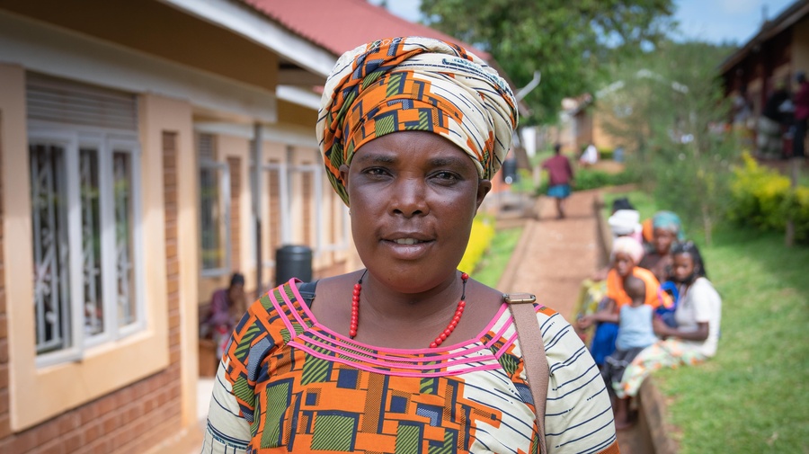 A woman stands on a pathway outside a row of buildings.