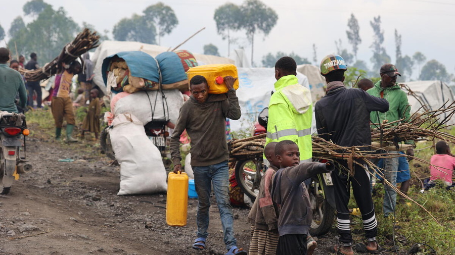 Families walk and ride, carrying their belongings, fleeing fighting in North Kivu.