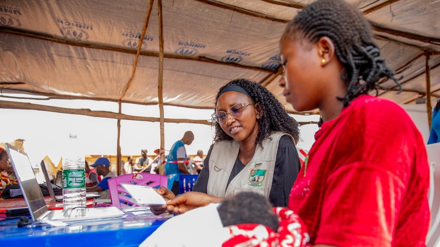 A woman siting in a UNHCR registration centre while holding her baby